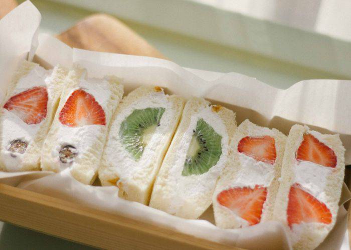 Japanese fruit sandwiches cut in half, revealing strawberries, blueberries and kiwi.